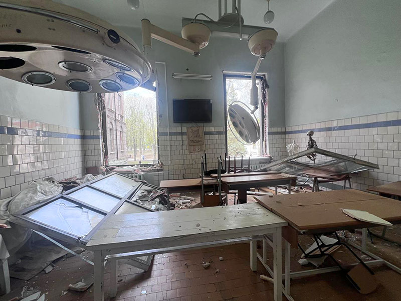 A blown-out operating room littered with broken equipment and debris.