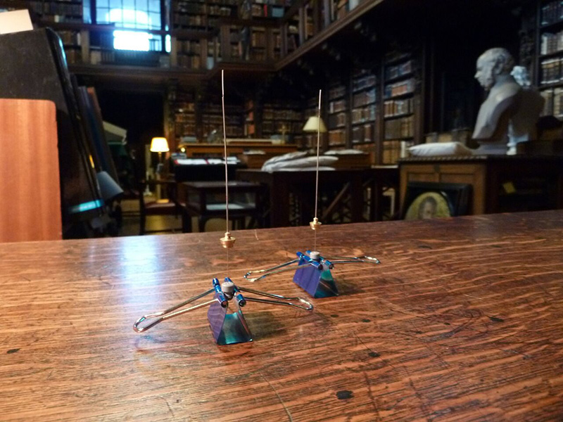 Two spindly air- sampling instruments sit on a wooden desk in a historic library.