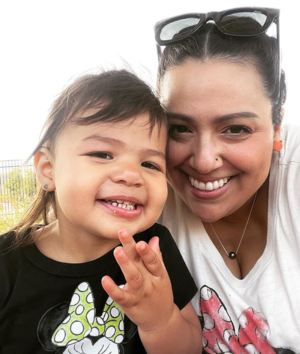 Photo of a woman and her young daughter, both smiling brightly.