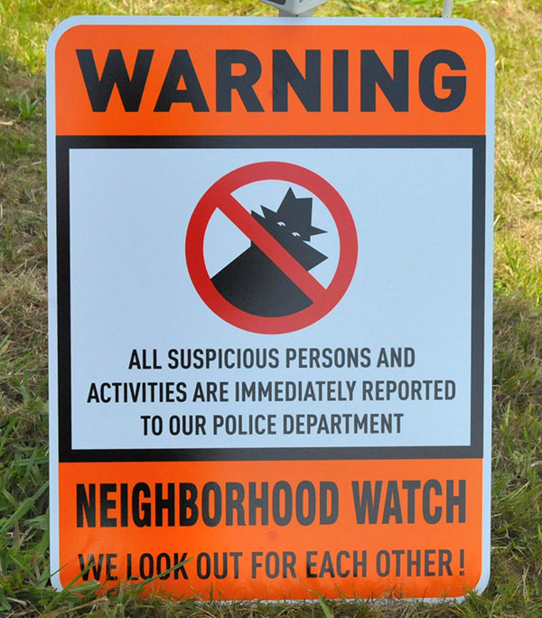 pOrange and white “Neighborhood Watch” sign with a silhouette of a person and warning against suspicious doings.