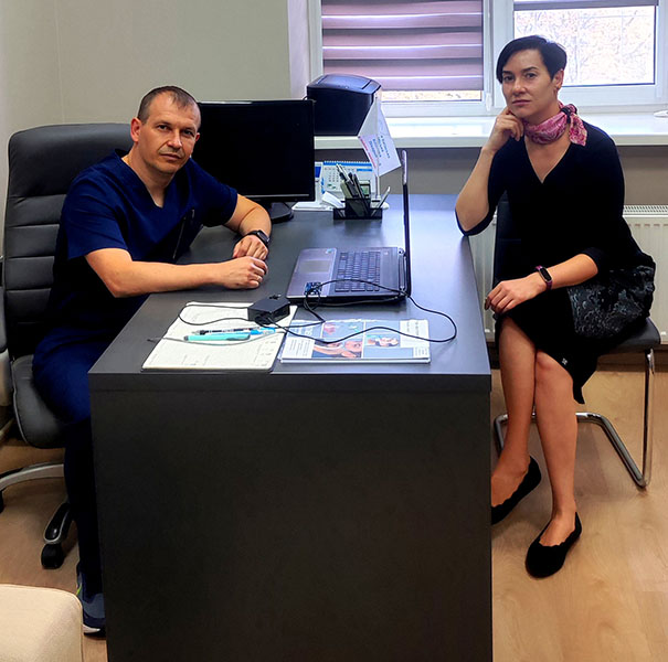 A man seated behind an office desk and a women seated on the other side of the desk, both with somber faces.