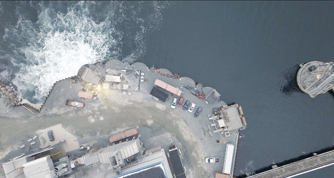 Overhead view of small buildings next to a seawater outfall.