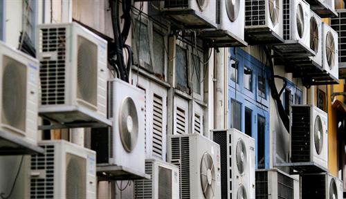 Photograph of dozens of air conditioners on the side of a building.
